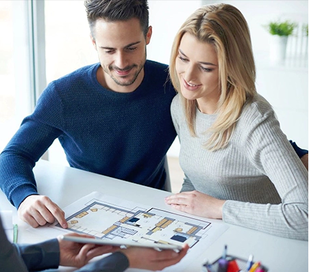 A man and woman looking at an item on the table.